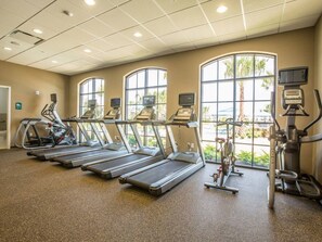Et fitnesscenter med løbebånd, crosstrainere og spinningcykler, store vinduer og et loft med indbygningsbelysning.