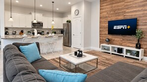 A modern living room with a sofa, coffee table, and a TV displaying ESPN+.