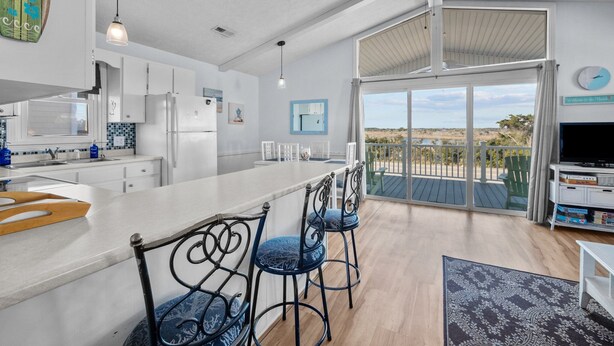 A spacious kitchen with a large island, white cabinetry, and a view to the outdoors. - Pets OK Beach Home+Short Walk Beach Access+Views! Recent Updates & Upgrades (Surf City)