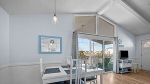 A spacious room with a dining table, chairs, a television, and a view of the outside. - Pets OK Beach Home+Short Walk Beach Access+Views! Recent Updates & Upgrades (Surf City)