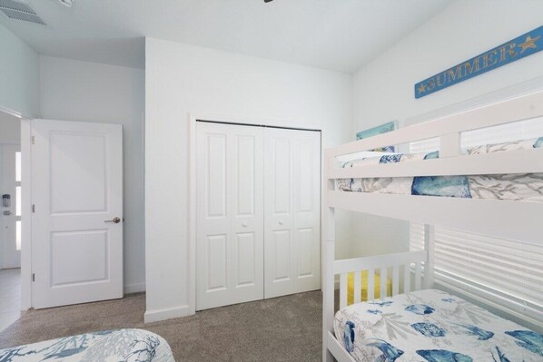 Habitación infantil con literas, una puerta blanca y un cartel que dice 'SUMMER'.