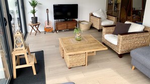 A living room with a television, wicker furniture, a guitar, and a bookshelf. - T4 family home 3 km from the beach (Anglet)