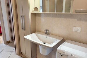 A bathroom with a white sink, a mirror, and a washing machine.