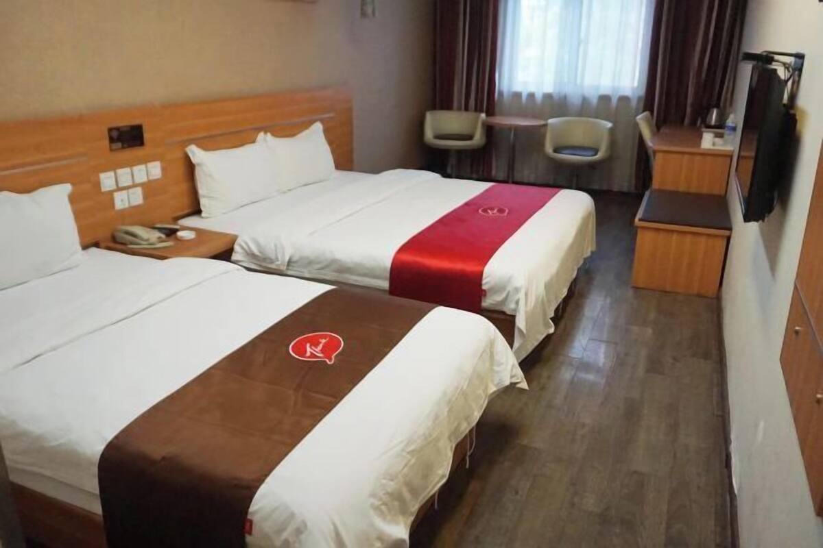 Ett hotellrum med två sängar, ett skrivbord, en stol och ett litet bord.