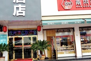 A storefront with a digital display and potted plants outside. - Neixiang Youshang Hotel (Neixiang)