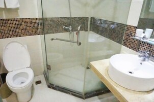 Un baño con ducha de vidrio, inodoro blanco y lavabo con espejo.