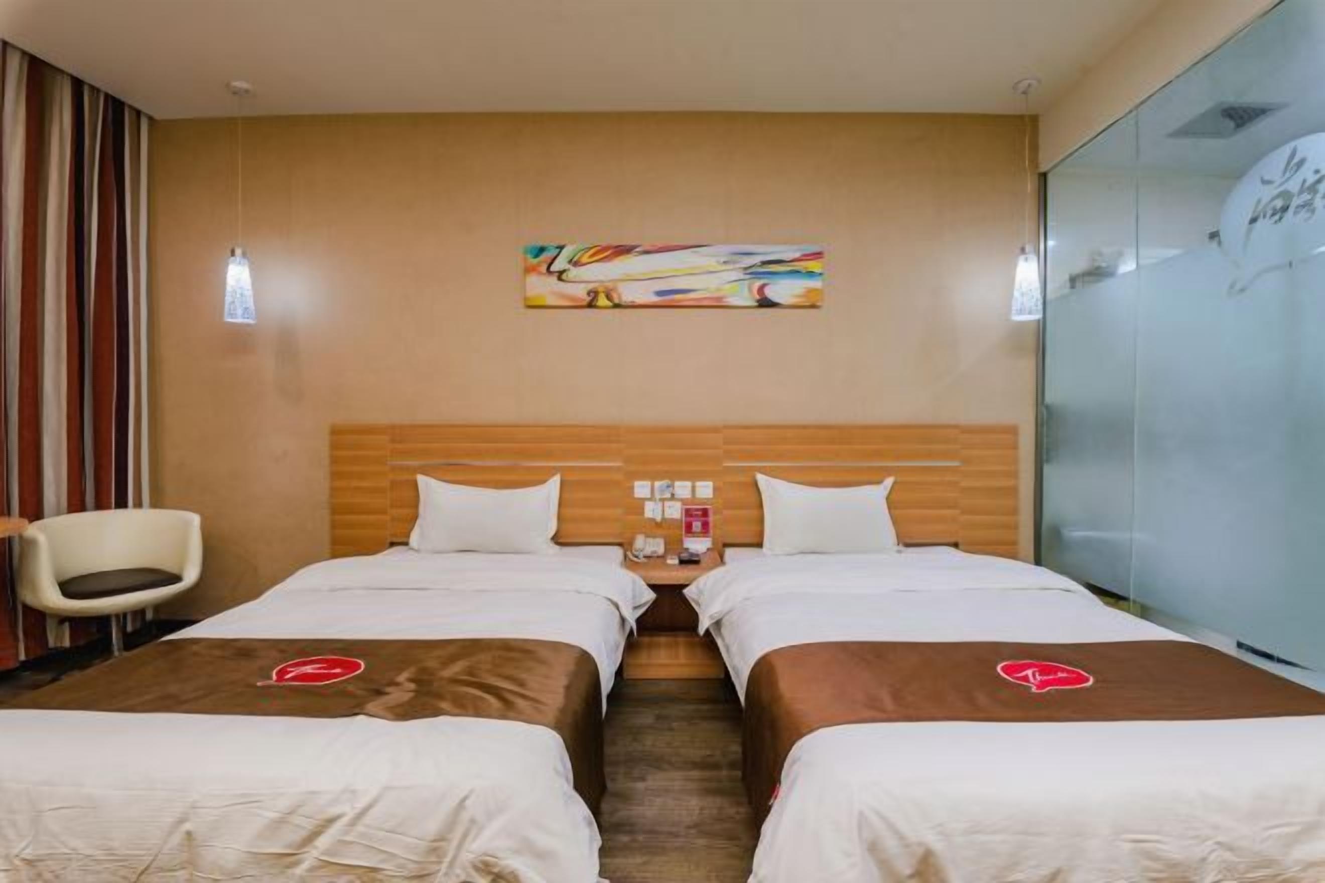 A hotel room with two beds, a wooden headboard, a painting on the wall, and a chair.