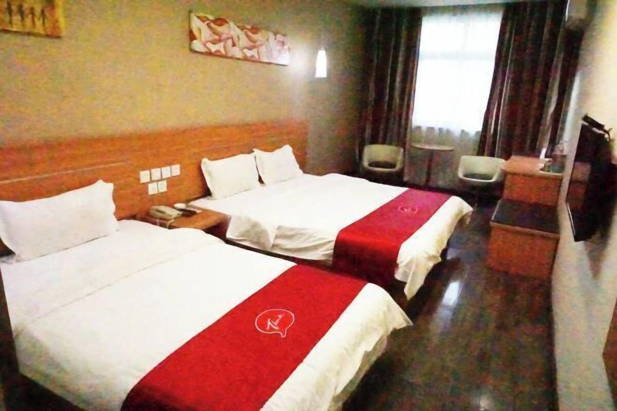 Ett hotellrum med två sängar, ett skrivbord, en stol och ett litet bord.