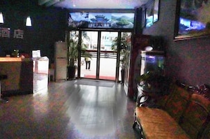 Vestíbulo de hotel con mostrador de recepción, zona de estar y un amplio ventanal que da al exterior.