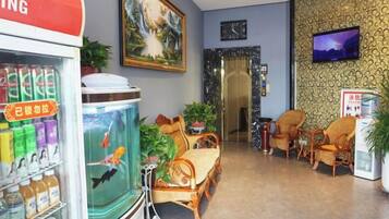 A hotel lobby with a fish tank, seating area, and a television on the wall.