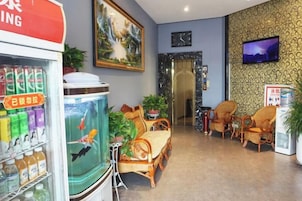 Un vestíbulo de hotel con un acuario, una zona de estar y un televisor en la pared.