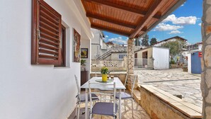 A patio with a table and chairs, a wooden ceiling, and a stone wall. - Holiday home Hana with air conditioning and sea views (Pula)