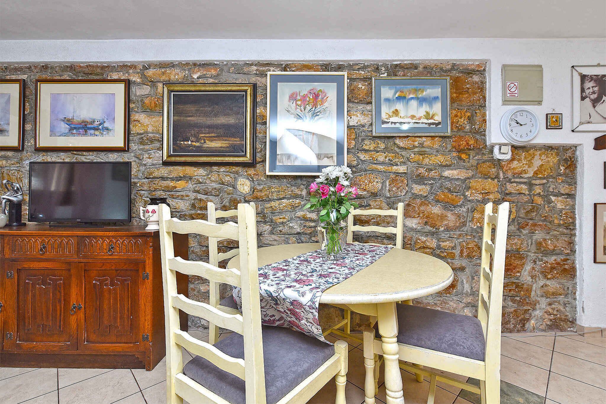 A dining area with a stone wall, wooden furniture, and framed artwork.