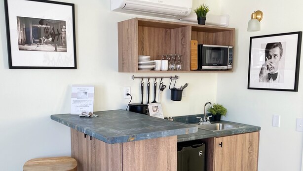 Una cocina moderna con una isla central, taburetes de bar, microondas y un lavamanos.