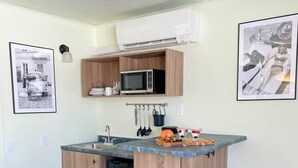 Una cocina compacta con armarios de madera, un microondas integrado y una pequeña isla con taburetes.