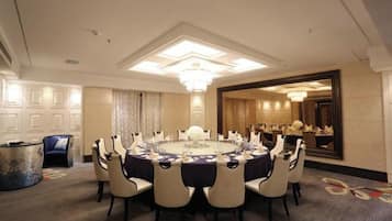 A conference room with a round table, chairs, and a chandelier.