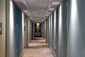 A hotel hallway with a carpeted floor, doors on both sides, and a reception area at the end. - Hangzhou Fuyang Blue Diamond International Castle Hotel (Hangzhou)