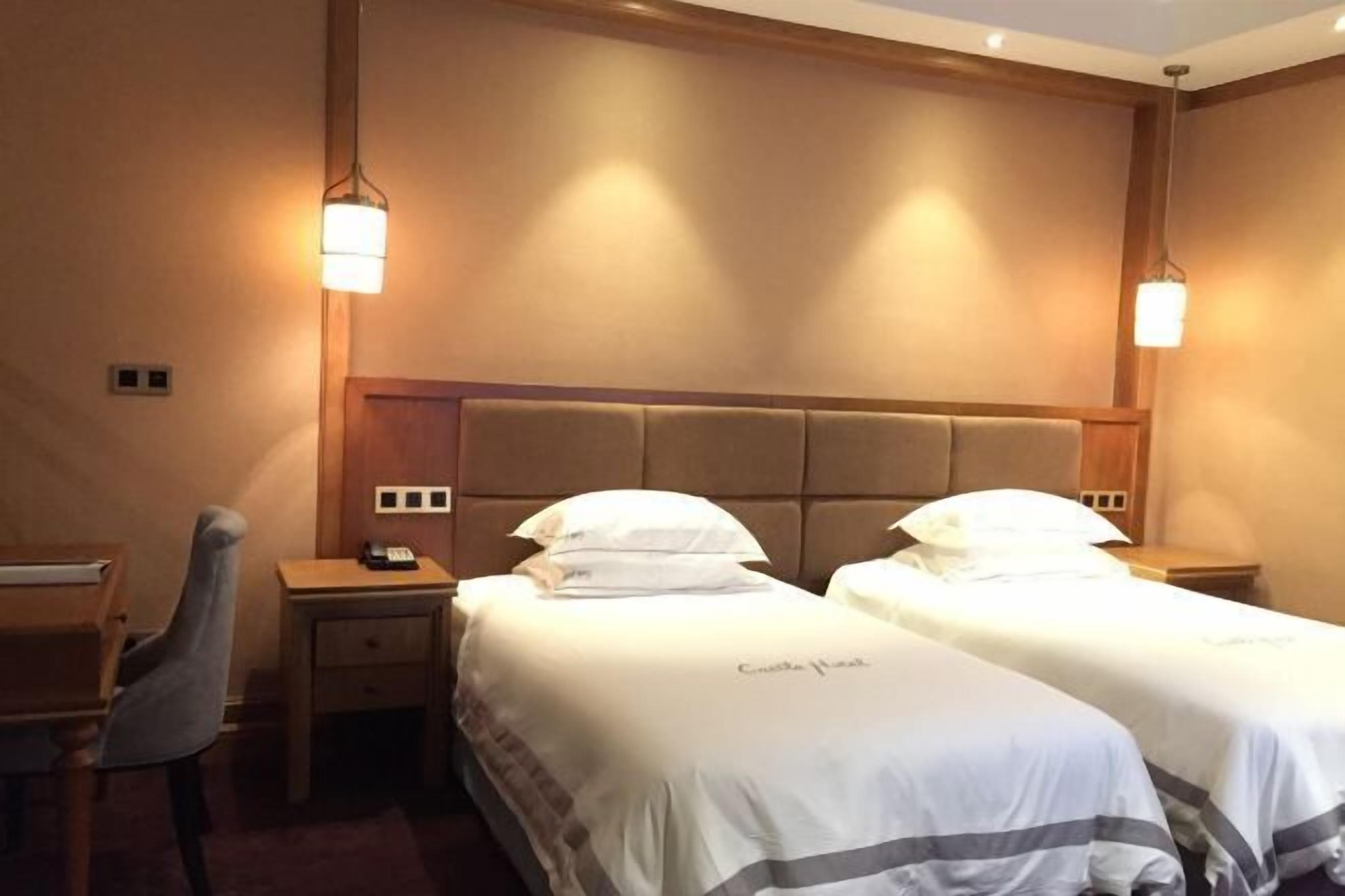 A hotel room with two beds, a desk, and a chair.