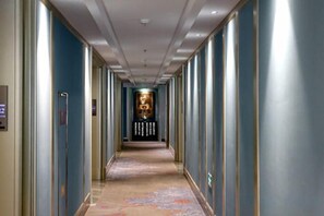 A hotel hallway with a carpeted floor, doors on both sides, and a central wall with a decorative panel. - Hangzhou Fuyang Blue Diamond International Castle Hotel (Hangzhou)
