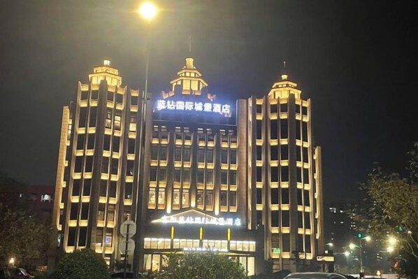 A multi-story building with illuminated signage, likely a hotel or corporate building, featuring a prominent entrance and vertical lines. - Hangzhou Fuyang Blue Diamond International Castle Hotel (Hangzhou)