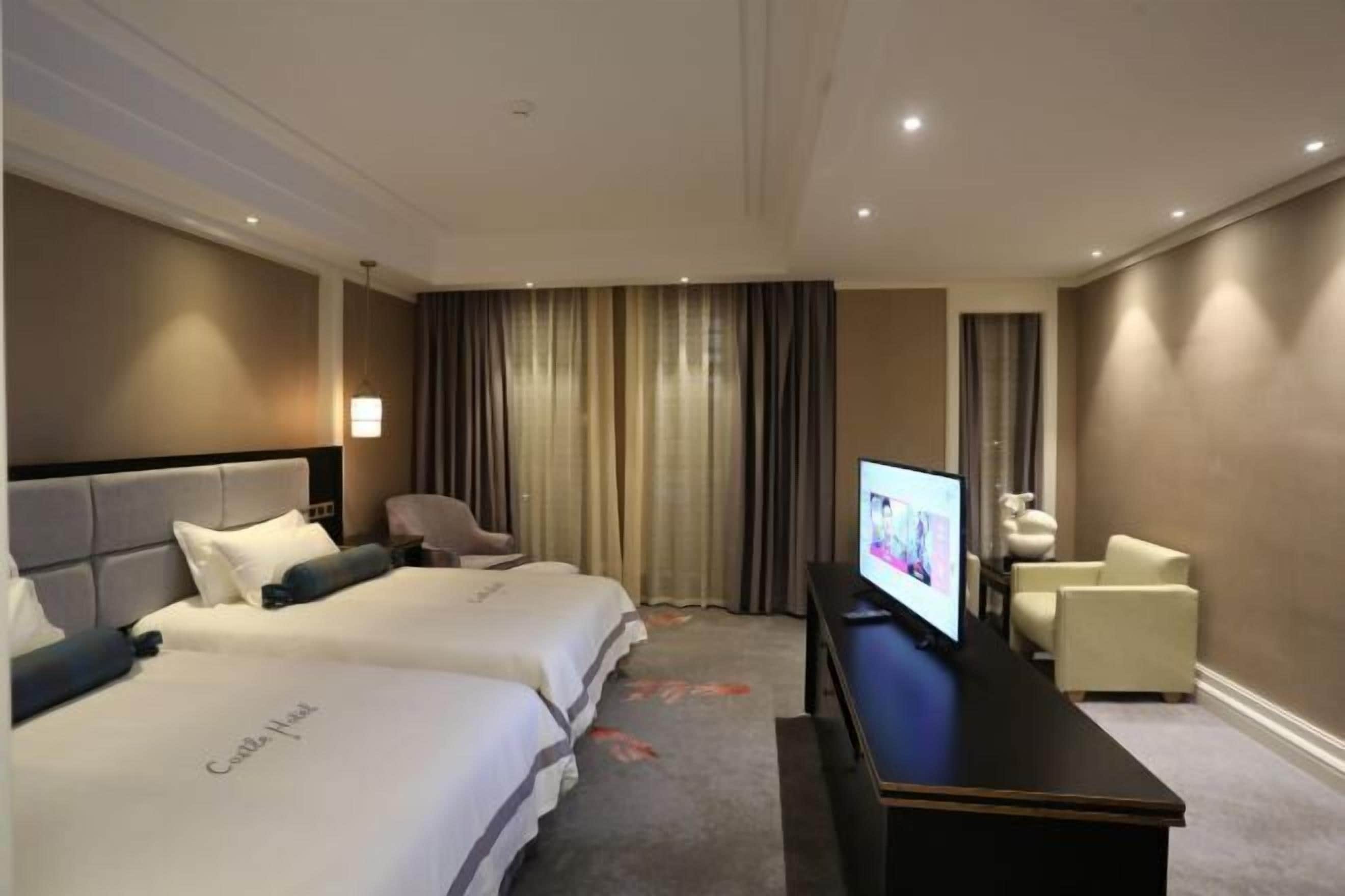 A hotel room with two beds, a flat-screen TV, a desk, and a chair.