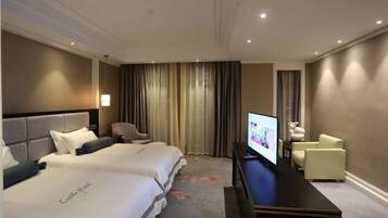 A hotel room with two beds, a flat-screen TV, a desk, and a chair.