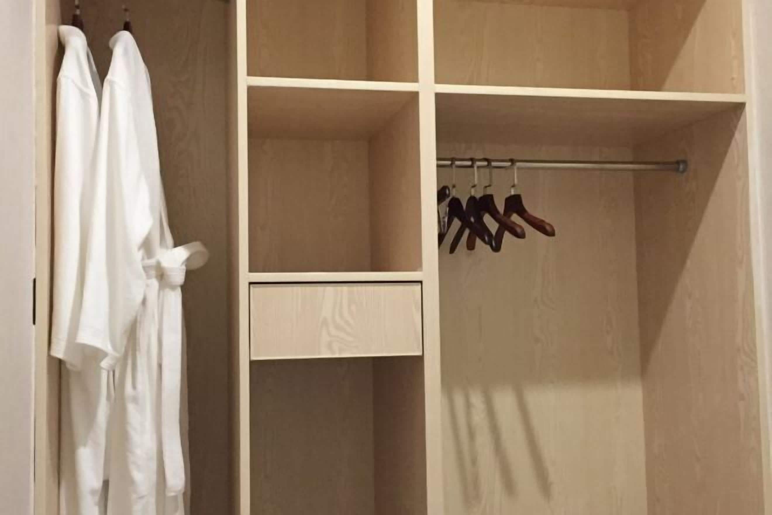 Un dressing avec espace pour suspendre les vêtements et un petit meuble à tiroirs.