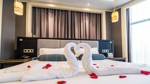 A hotel room with a bed, a nightstand, a lamp, and a window with curtains. - Hangzhou Fuyang Blue Diamond International Castle Hotel (Hangzhou)