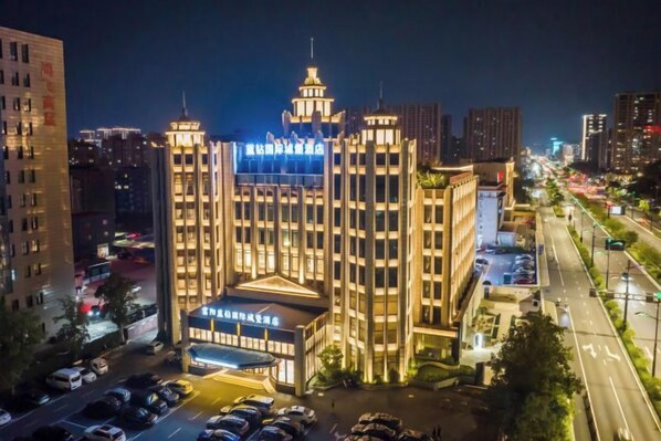 A multi-story hotel with a central atrium, parking lot, and a street view with traffic. - Hangzhou Fuyang Blue Diamond International Castle Hotel (Hangzhou)