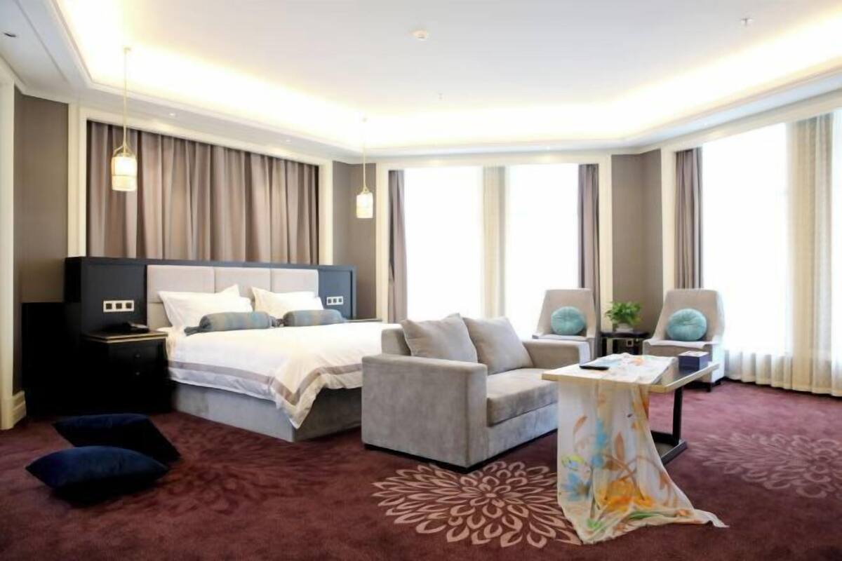 Ein modernes Hotelzimmer mit einem großen Bett, einer Sitzecke, einem kleinen Tisch und einem Schreibtisch.