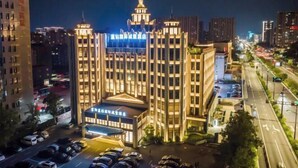 A multi-story hotel with a prominent central tower, large windows, and a well-lit facade. - Hangzhou Fuyang Blue Diamond International Castle Hotel (Hangzhou)
