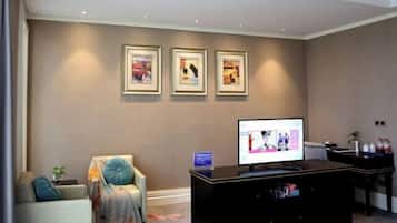 A modern living room with a flat-screen TV, a sofa, a coffee table, and framed artwork on the wall.
