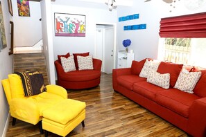 A living room with a yellow armchair, red sofas, and a wooden staircase. - Canyon-View 4BR Home with Hot Tub & Fire Pit, 15 Min to Downtown (San Diego)