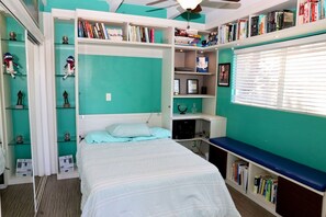 A bedroom with a bed, a ceiling fan, a bookshelf, and a window with blinds. - Canyon-View 4BR Home with Hot Tub & Fire Pit, 15 Min to Downtown (San Diego)