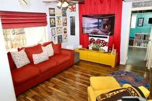A living room with a red sofa, yellow cabinet, and a television. - Canyon-View 4BR Home with Hot Tub & Fire Pit, 15 Min to Downtown (San Diego)