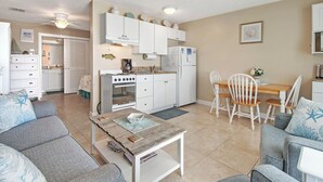 Un espacio habitable compacto con kitchenette, comedor y dos sofás grises con estampados de estrellas.