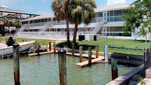 Un puerto deportivo con barcos amarrados, un edificio con balcón y una zona cubierta de césped.