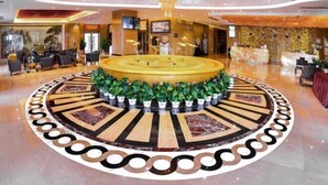 En lobby med et centralt cirkulært siddeområde, en receptionsdisk og en lysekrone.