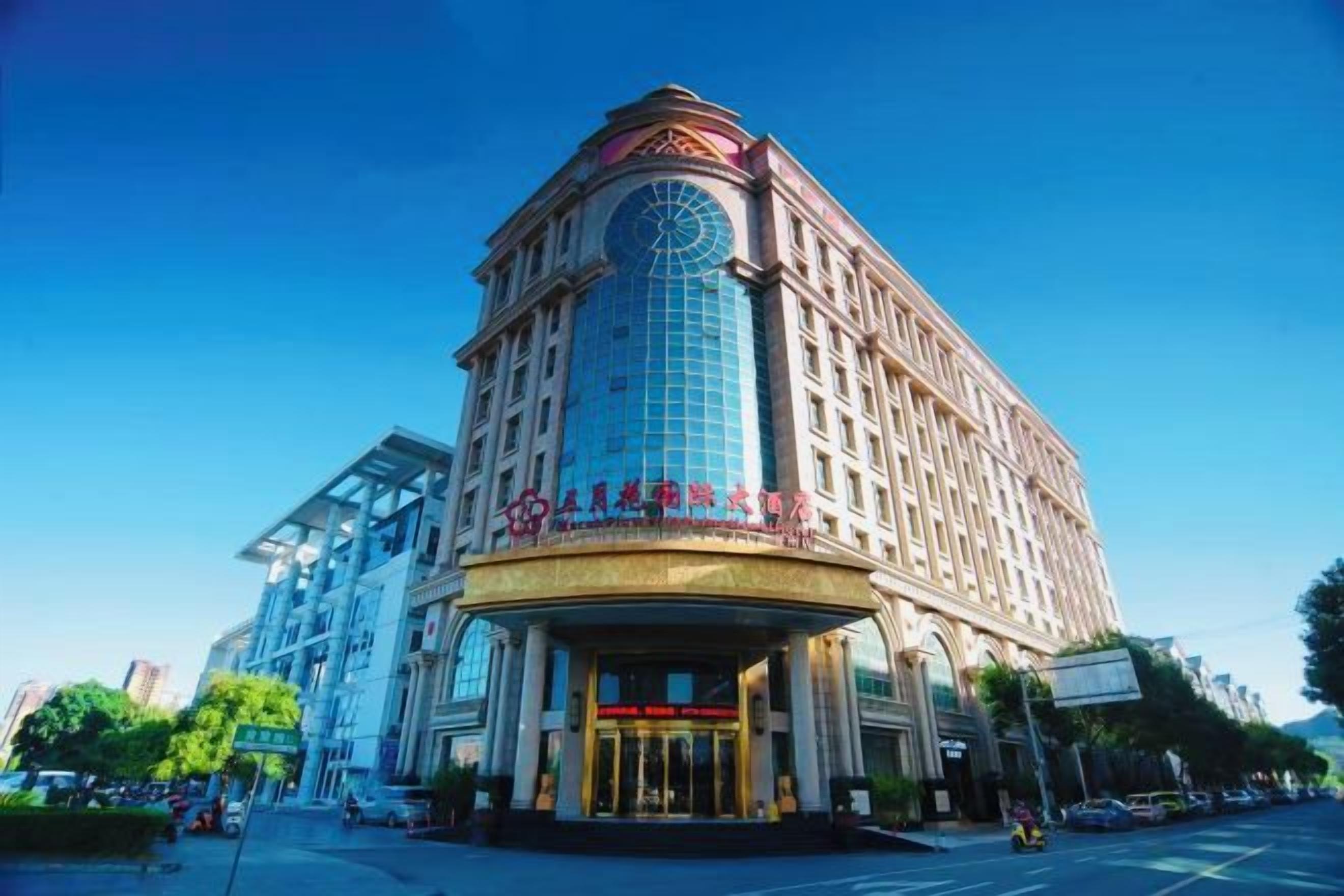 A multi-story hotel with a prominent clock tower, a large glass facade, and a grand entrance.