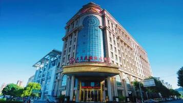 A multi-story hotel with a prominent clock tower, a large glass facade, and a grand entrance.