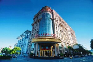 Un hotel de varios pisos con una imponente torre de reloj, un amplio frente de cristal y una entrada majestuosa.
