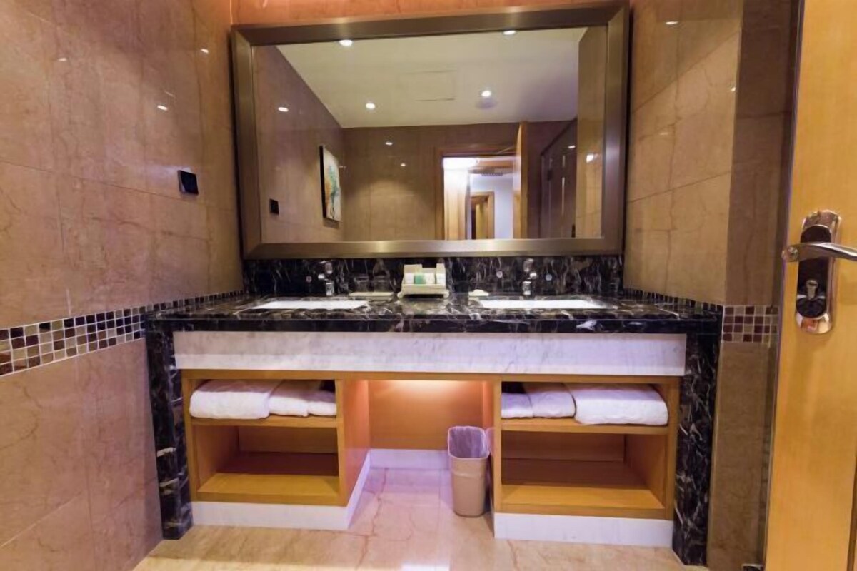 A bathroom with two sinks, a large mirror, and a towel rack.