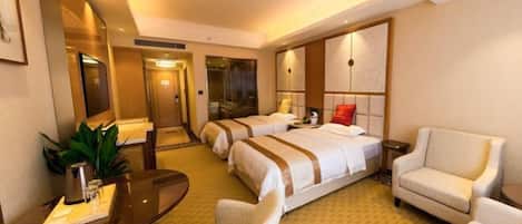 A hotel room with two beds, a desk with a chair, a sofa, and a large mirror.