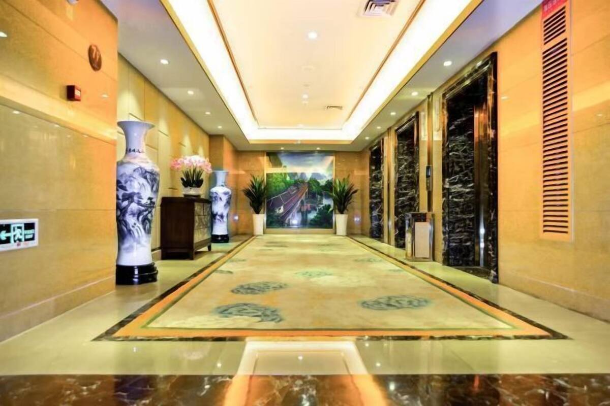 A hotel lobby with a marble floor, a central carpeted area, and a large mural on the back wall.