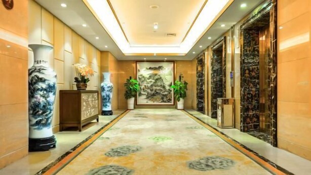 A hotel lobby with a marble floor, large vases, and a painting on the wall. - March Flower International Hotel (Hechi)