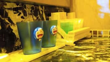 Una encimera de cocina con dos tazas azules con personajes de dibujos animados, una bandeja amarilla y un recipiente verde.