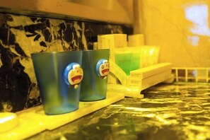 A kitchen counter with two blue cups featuring cartoon characters, a yellow tray, and a green container. - March Flower International Hotel (Hechi)