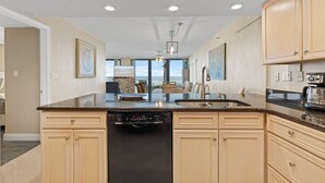 A modern kitchen with a dishwasher, a sink, and wooden cabinets. - Direct Oceanfront, Ground-Floor Condo Just Steps from Pool & Beach Access! (New Smyrna Beach)