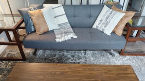 Un canapé gris agrémenté de coussins à motifs et une table basse en bois placée devant.