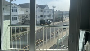 Vista desde un balcón sobre una calle residencial con casas, un camión estacionado y un cielo despejado.